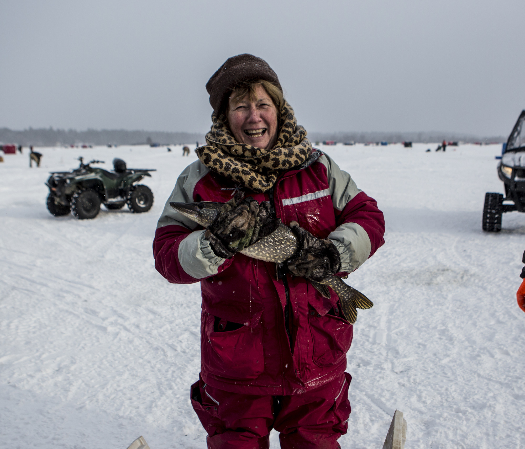 Woman holding a fish on a snowy lake.