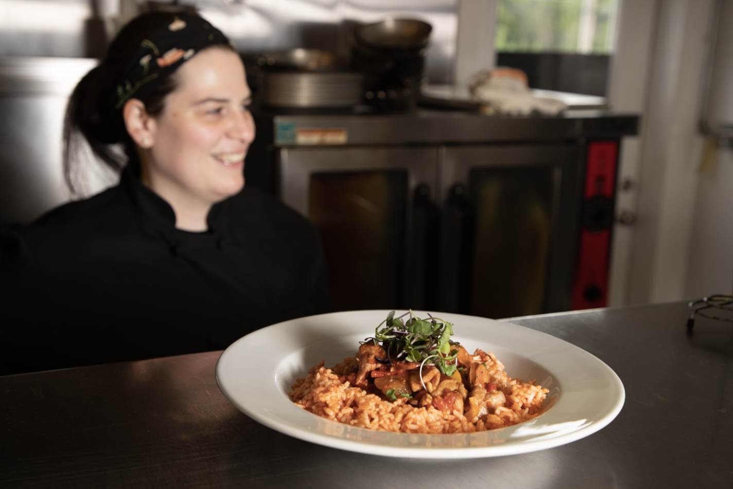 Chef stands behind a plate of pasta