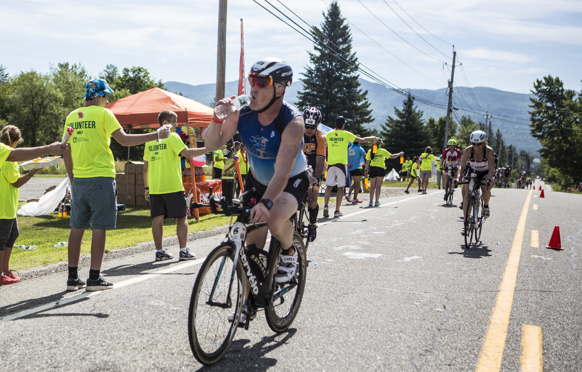 Bike athlete rides through aid station during the Lake Placid IRONMAN